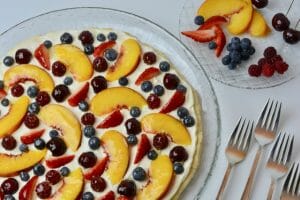 Glazed Fresh Fruit Pizza topped with sliced peaches, cherries, strawberries, raspberries and blueberries.
