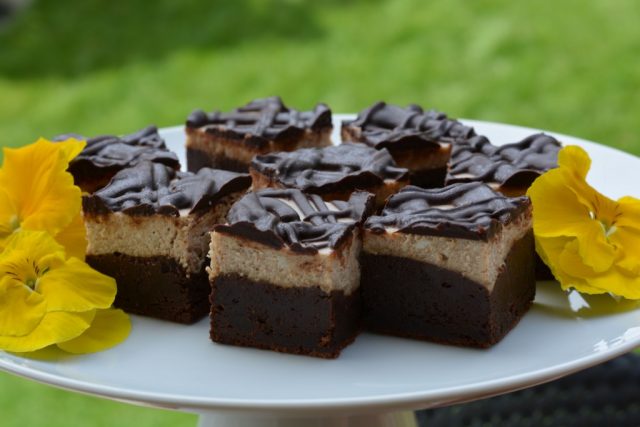 A pedestal tray with gluten free Mochaccino Cheesecake Brownies decorated with pansies.