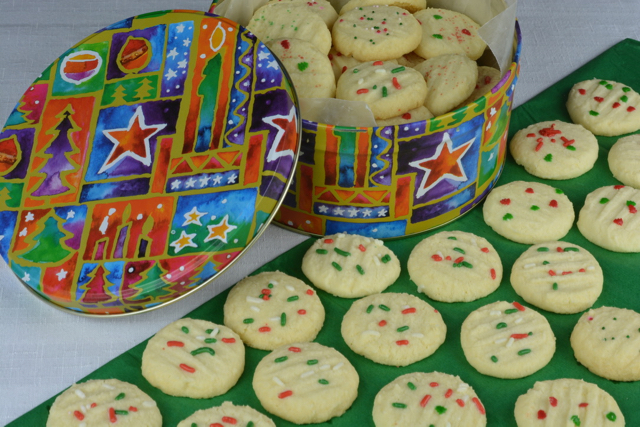A tin of gluten free Whipped Shortbread decorated with red and green sprinkles.