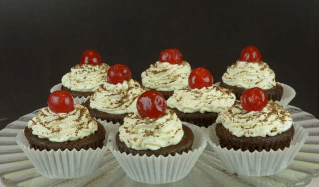 A tray of Black Forest Cupcakes topped with maraschino cherries