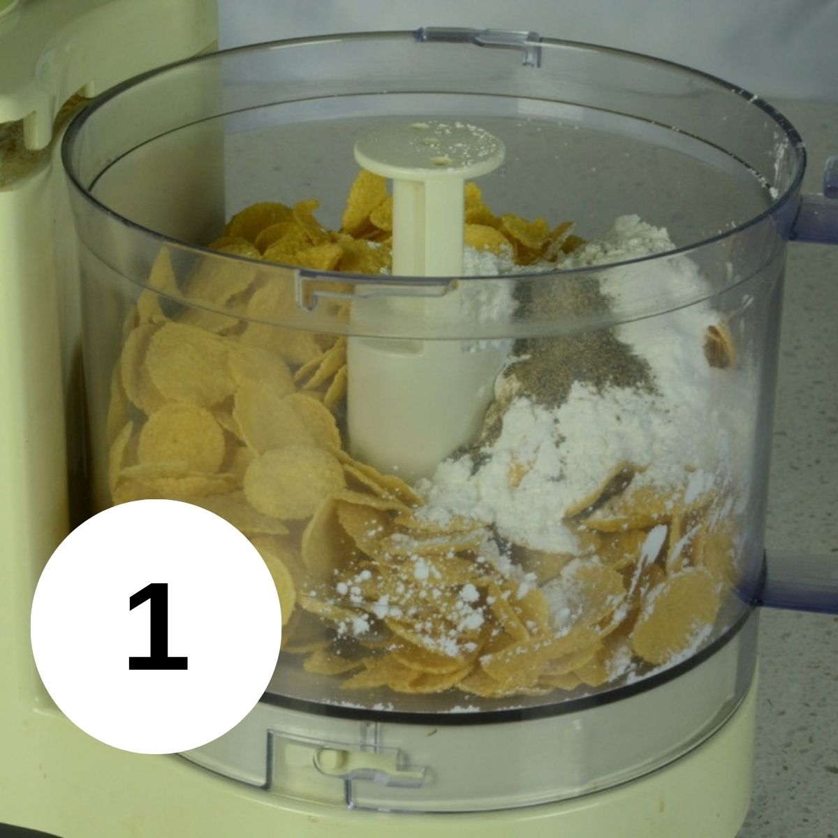 A food processor filled with cornflakes, cornstarch, salt and pepper.