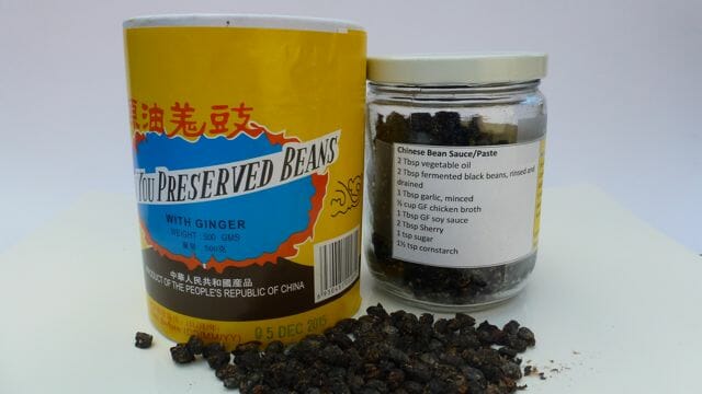 A container of Chinese black beans with a jar showing how I store them with the Black Bean Sauce recipe on the label.