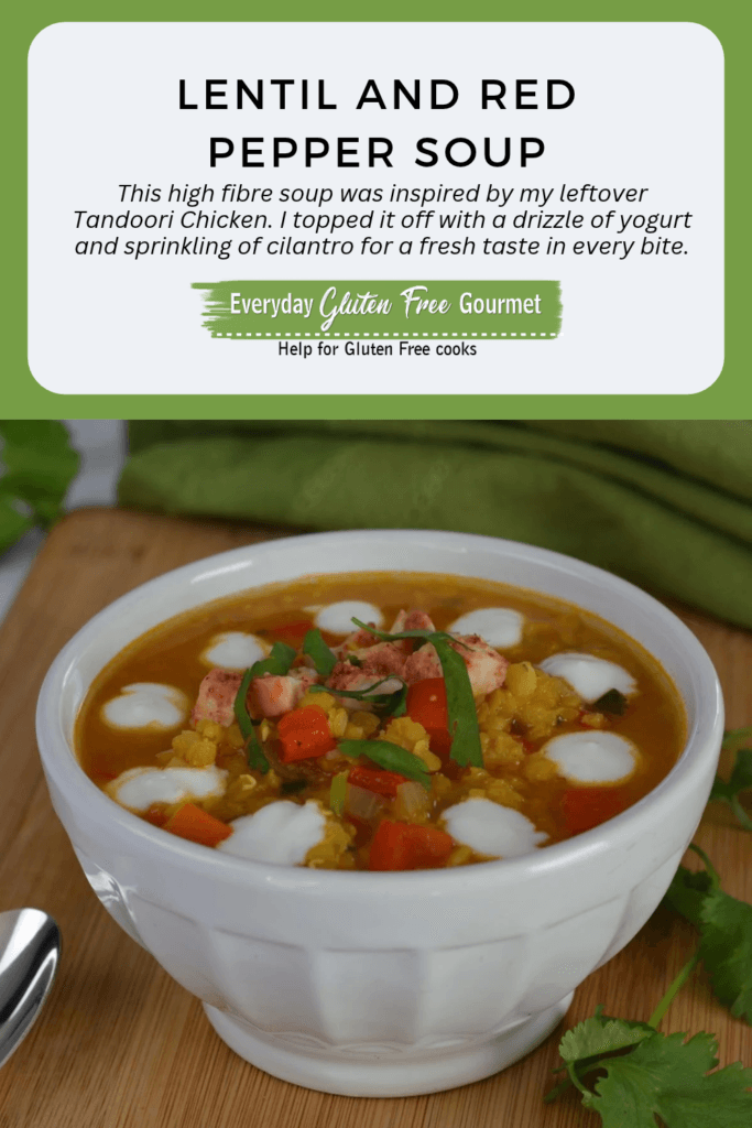 A bowl of Lentil and Red Pepper Soup with a circle of yogurt dots around the bowl and pieces of tandoori chicken added on top.