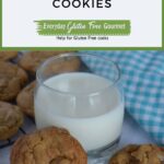 A glass of milk surrounded by chocolate chip cookies.