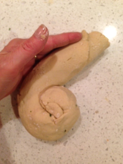 A log of Chinese onion bread being rolled into a circle.