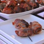 A white plate with 3 Chorizo Stuffed Bacon Wrapped Dates.