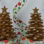 Gingerbread Cookie Christmas Trees made with 4 sizes of star cookies, in front of a white background with festive red and green ribbon around them.