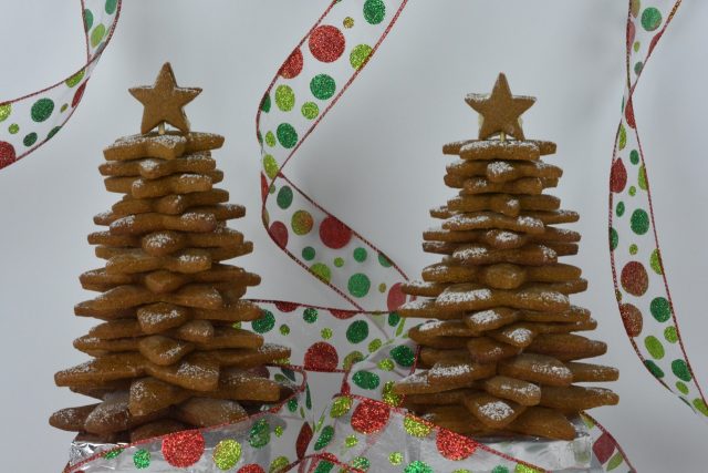 Gingerbread Cookie Christmas Trees made with 4 sizes of star cookies, in front of a white background with festive red and green ribbon around them.