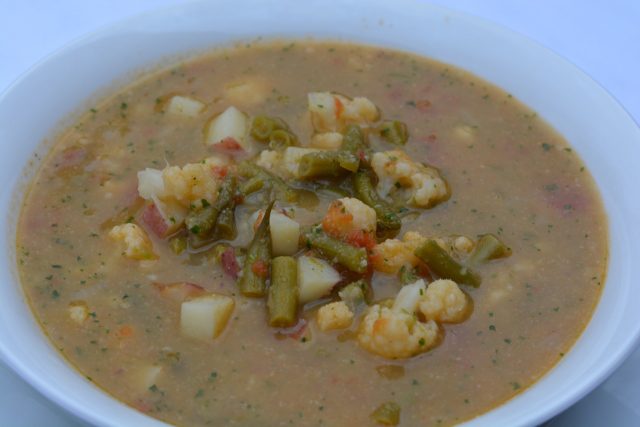 A bowl of Green Bean Soup with cauliflower, cilantro and parmesan.