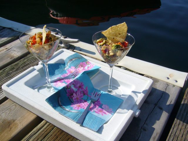 Grilled Shrimp Martinis with a nacho chip garnish, served on blue and pink napkins set on a dock with the reflection of a boat in the water.