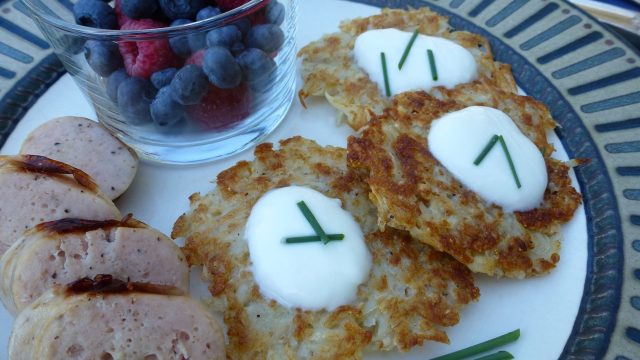 Three Potato Latkes topped with sour cream and a few snipped chives.