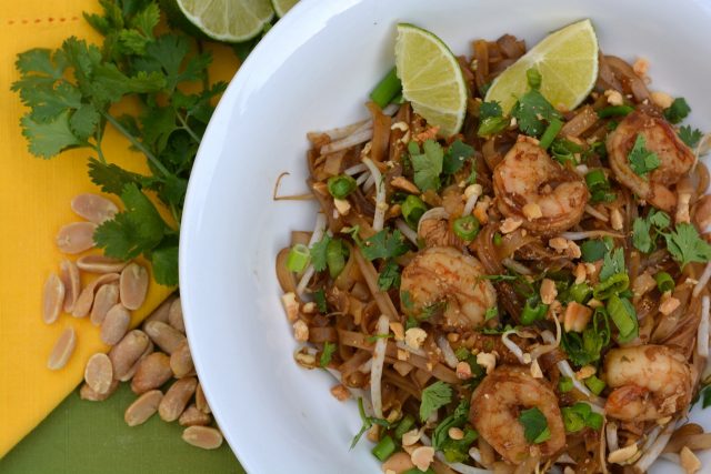 Shrimp Pad Thai topped with cilantro, chopped peanuts and lime wedges.