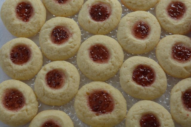 A plate of gluten free Thumbprint Cookies filled with raspberry jam.