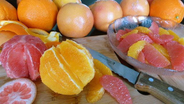 Citrus supremes surrounded by whole oranges and grapefruits.