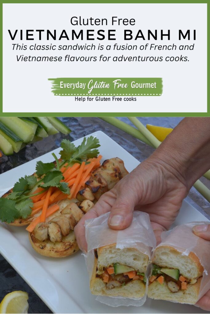 Someone holding a Vietnamese Banh Mi, a lemongrass chicken sandwich wrapped in wax paper and cut in half showing the carrot, cucumber and cilantro filling.