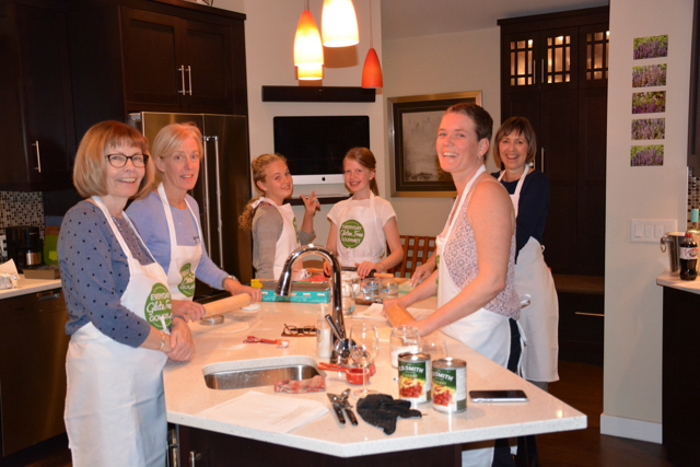 The Everyday Gluten Free Gourmet kitchen with 4 adults and 2 kids all at the counter cooking.An in Person Cooking Classes in Calgary