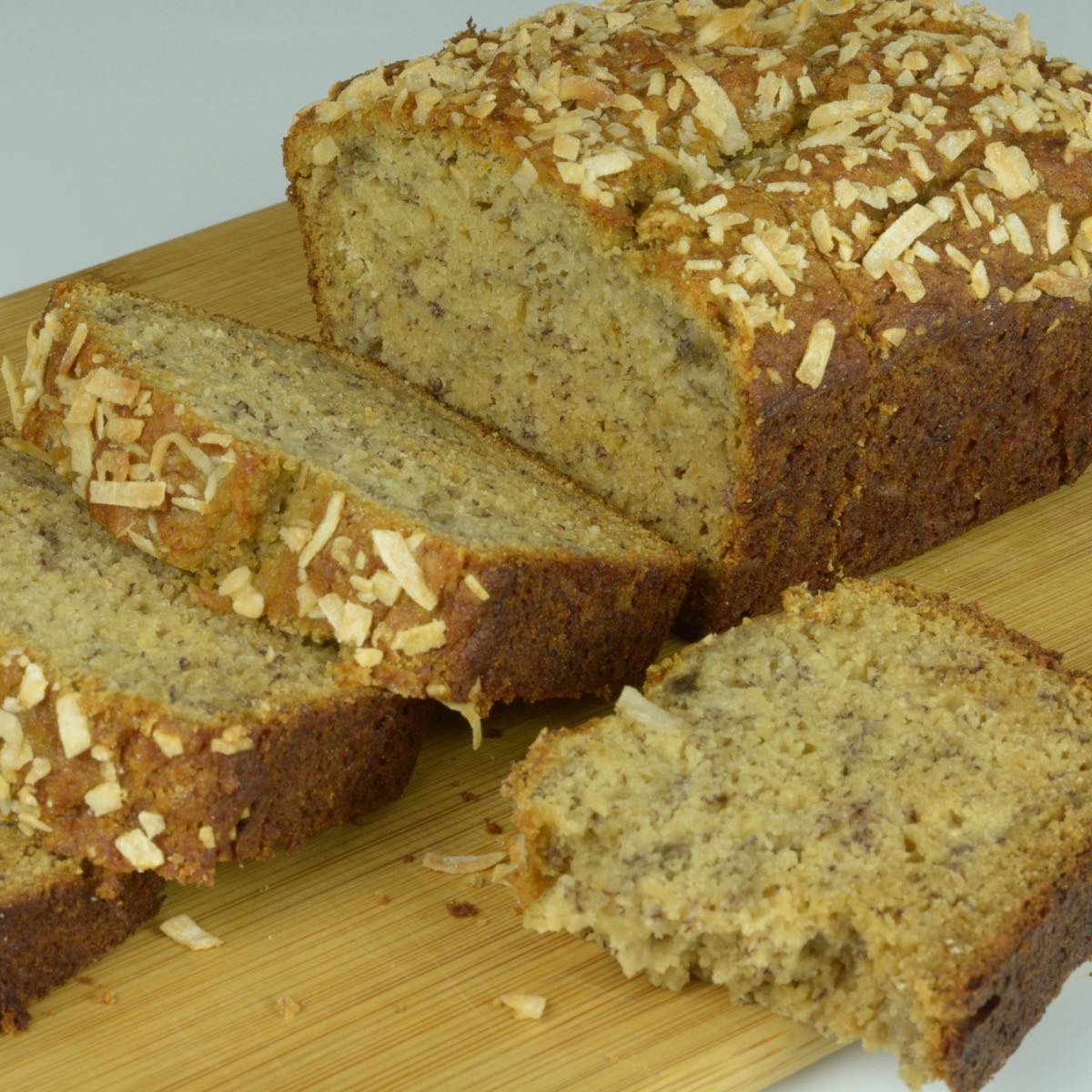 A loaf of coconut banana bread with slices showing the interior.