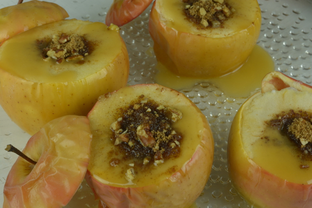 Close up of baked apples with cinnamon-sugar filling and caramel sauce on top.