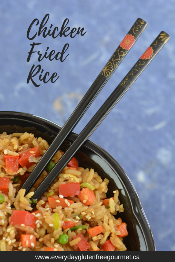 A bowl of Gluten Free Gluten free Chicken Fried Rice with fancy chopsticks coming out of it.