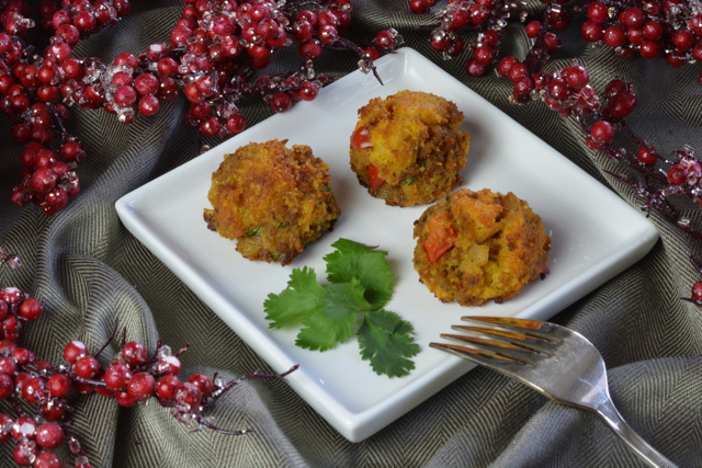 Three Cornbread Sausage Stuffing Balls on a small white plate surrounded by artificial candied cranberries.