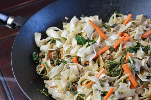 A wok full of Beef and Bok Choy with rice noodles.