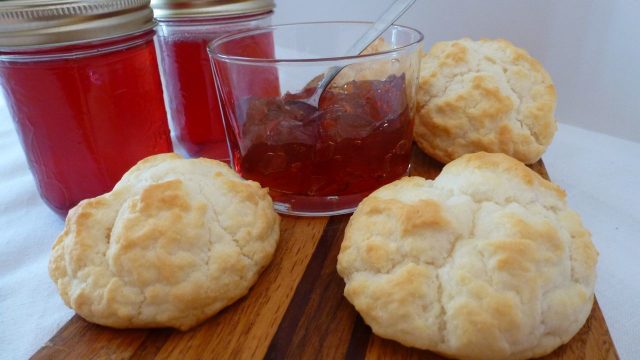 Gluten free buttermilk biscuits on a board with homemade crab apple jelly.