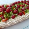 A rectangular Holiday Pavlova filled with cream and fresh strawberries, raspberries and kiwi fruit.