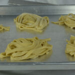 Nests of homemade gluten free pasta drying on a baking sheet.