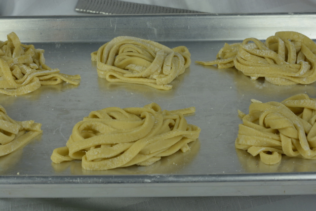 Nests of homemade gluten free pasta drying on a baking sheet.