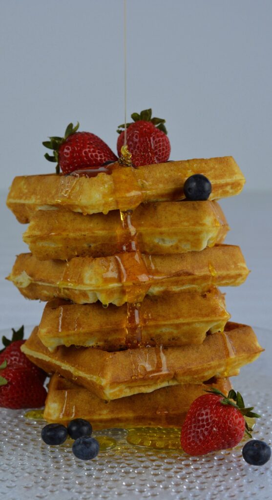 A stack of gluten free waffles dripping with syrup and ready to eat.