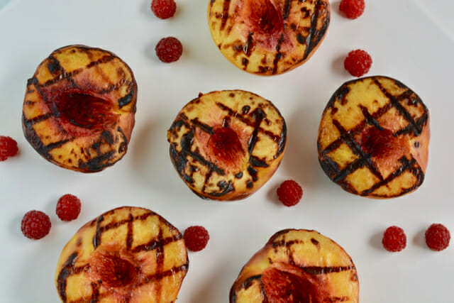 Grilled Peaches with raspberries on a white background.