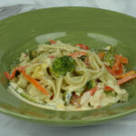 A plate of gluten free Pasta Primavera sprinkled with freshly grated Parmesan cheese.