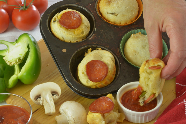 A tray of Pepperoni Pizza Cheese Buns and someone dipping theirs into the pizza dipping sauce.