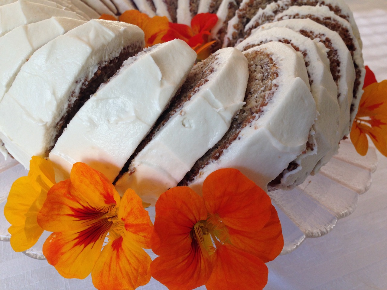 Slices of Banana Bundt Cake with Cream Cheese Icing garnished with fresh nasturtiums.