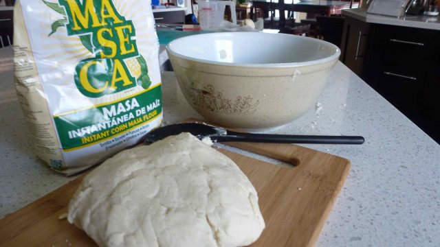 A fresh masa dough beside a bag of masa harina