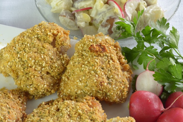 Three pieces of Sesame Baked Chicken with potato salad and radishes.