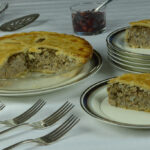Tourtiere cut to serve with cranberry chutney on the side.