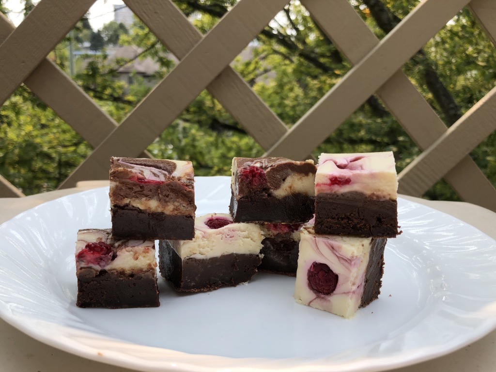 Raspberry Swirl Cheesecake Brownies cut on a plate and ready to eat.