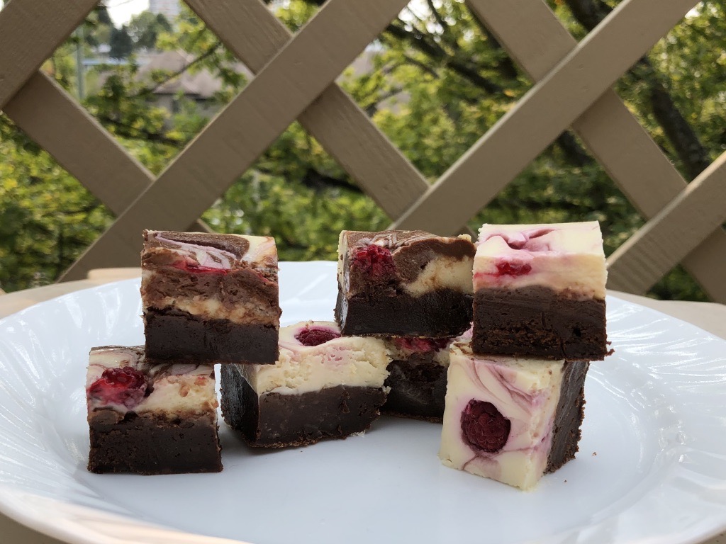 Raspberry Swirl Cheesecake Brownies cut on a plate and ready to eat.