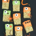 A tray of Rice Krispie square each dipped in melted chocolate with a googly eye at the top.