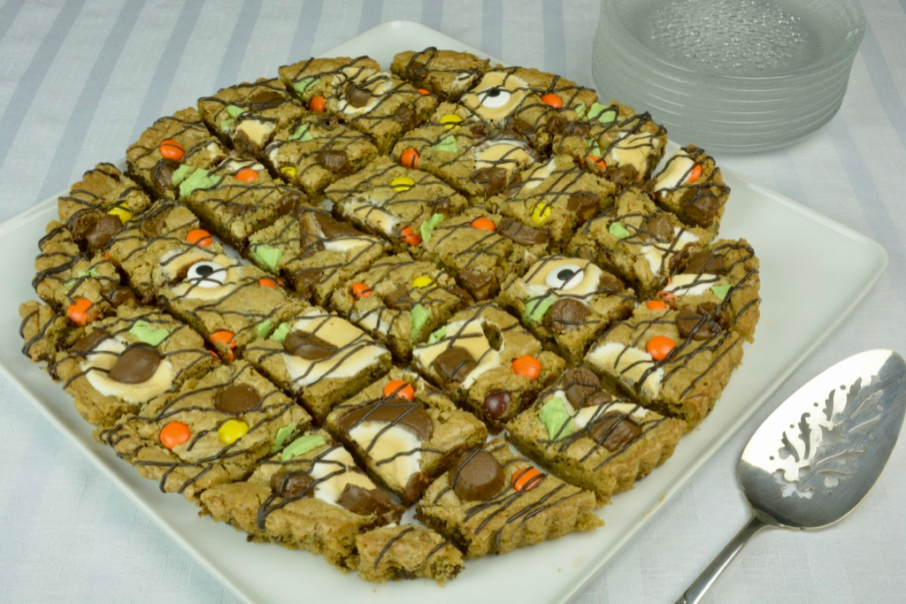 A 12-inch round cookie pizza decorated with colourful candy, melted chocolate, peanut butter cups and a few googly eyes for Halloween.