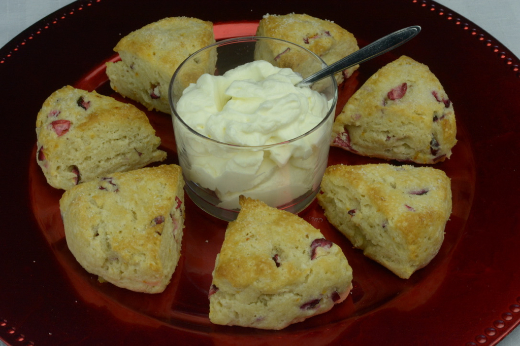 Mini Cranberry Orange Scones served on a red tray with whipped cream.