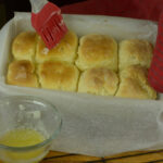 The final brushing of melted butter on soft dinner rolls while still warm.