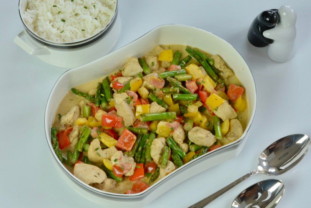 A serving dish of Chicken in Madeira Cream Sauce, asparagus, red and yellow peppers.
