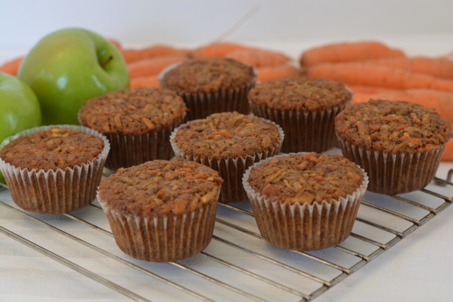 A rack of Morning Glory Muffins fresh from the oven surrounded by carrots and apples.