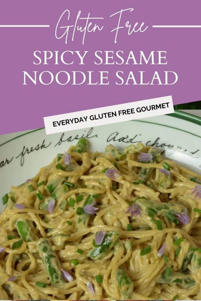 A bowl of noodles with green beans tossed with a mayonnaise dressing and garnished with the purple petals from a chive blossom.