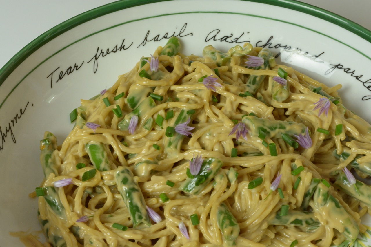 A close up of Spicy Sesame Noodle Salad with green beans and a sprinkling of fresh chives and purple chive blossoms.
