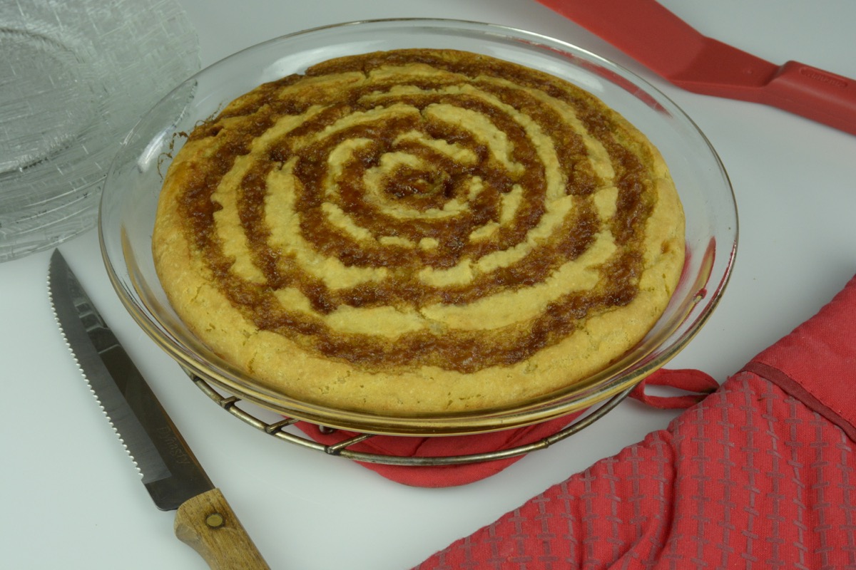A cooked pancake bake in a pie plate with a circular pattern of cinnamon butter covering the entire pie.