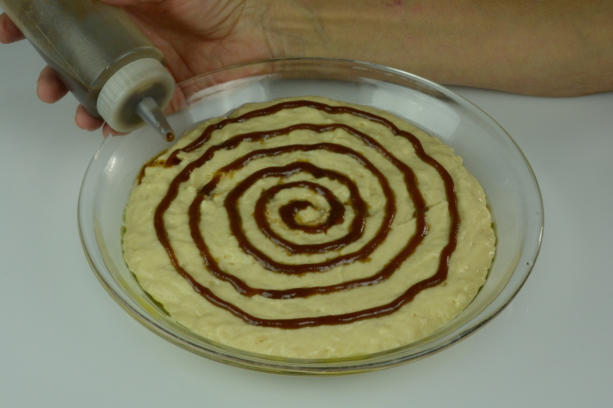 A pie plate of pancake batter with a circular pattern of cinnamon butter covering the entire pie.