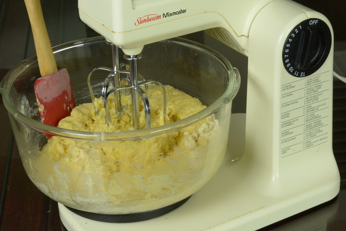 A bowl in a stand mixer beating the ingredients for cornbread.